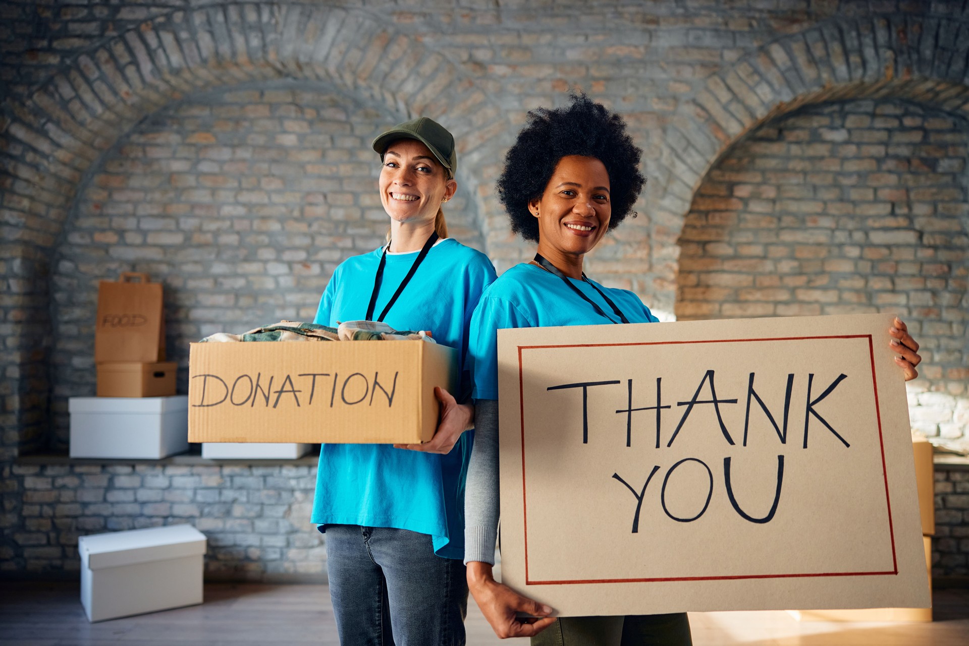 Happy women volunteering at charitable foundation and looking at camera.